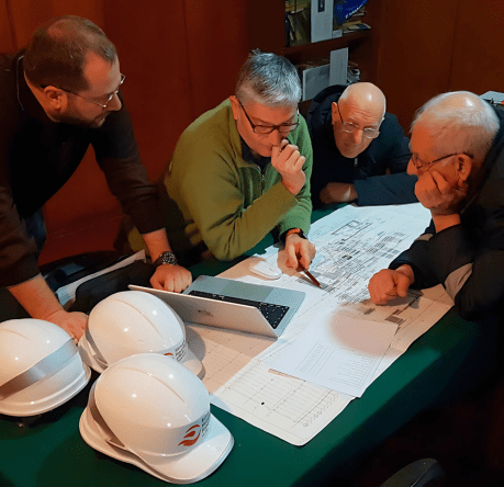 Close-up of engineers in PPE discussing steel plant investment opportunities.
